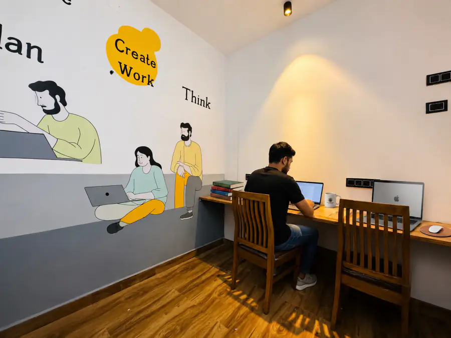 Guest working with a laptop in the HOSHTEL99 Delhi coworking room